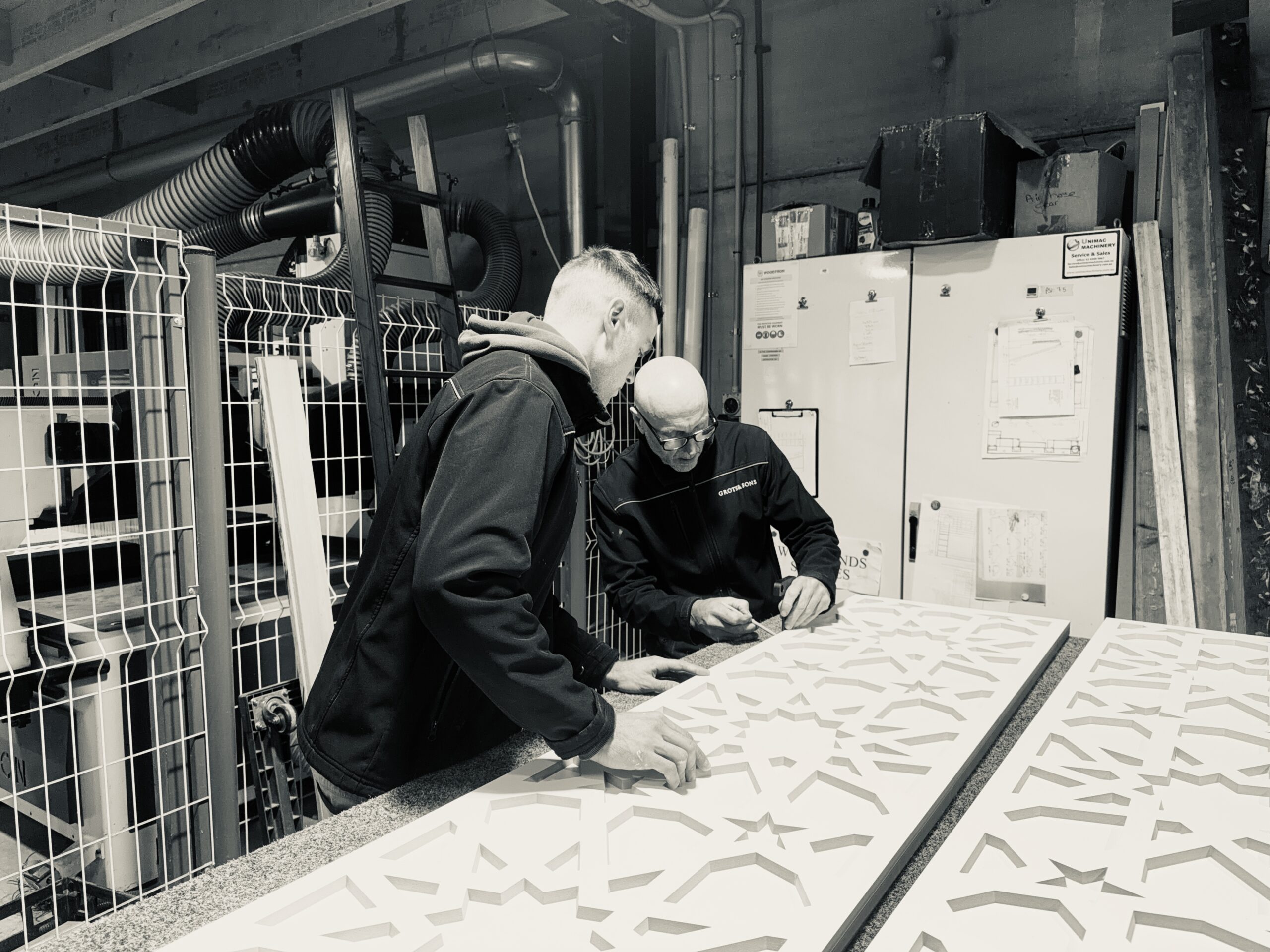 Amos and Oscar Groth reviewing a custom decorative panel in the Groth & Sons workshop