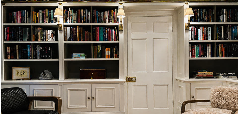 Traditional built in bookcases with detailed cabinetry and brass library rail